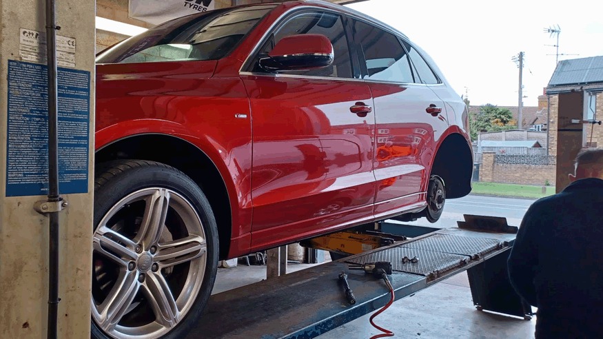 Red Audi Q5 raised on the lift with a wheel off