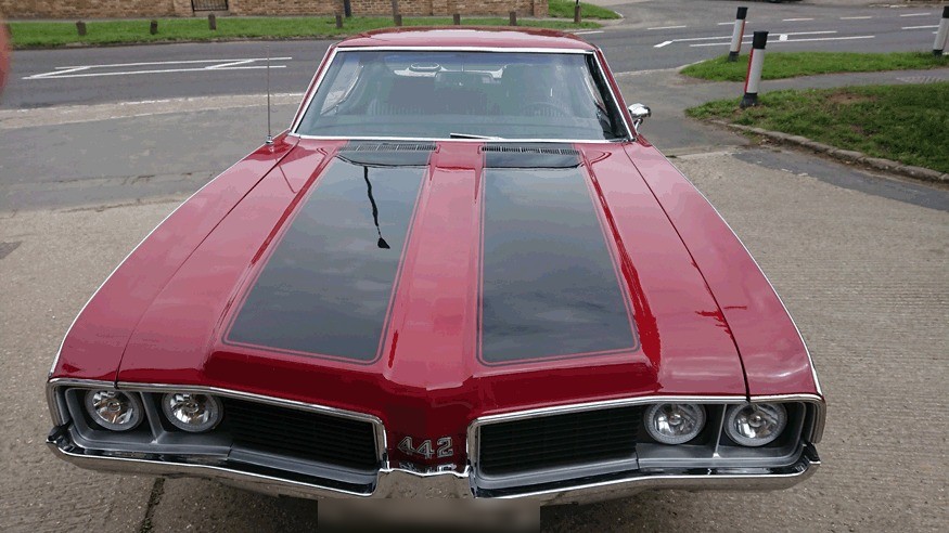 Red Oldsmobile 442 with black bonnet stripes parked outside
