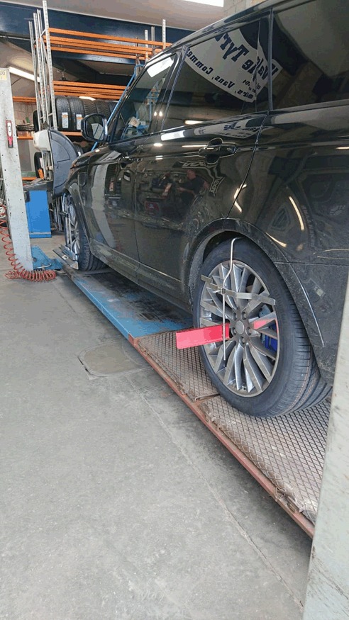 Laser alignment clamp fitted to the wheel of a black Range Rover on the ramp