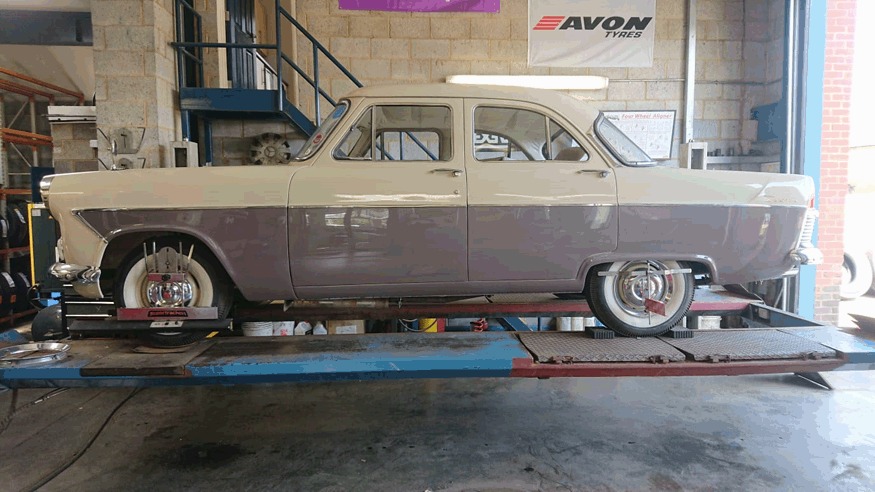 Classic two-tone Ford Zodiac raised on the ramp in the workshop