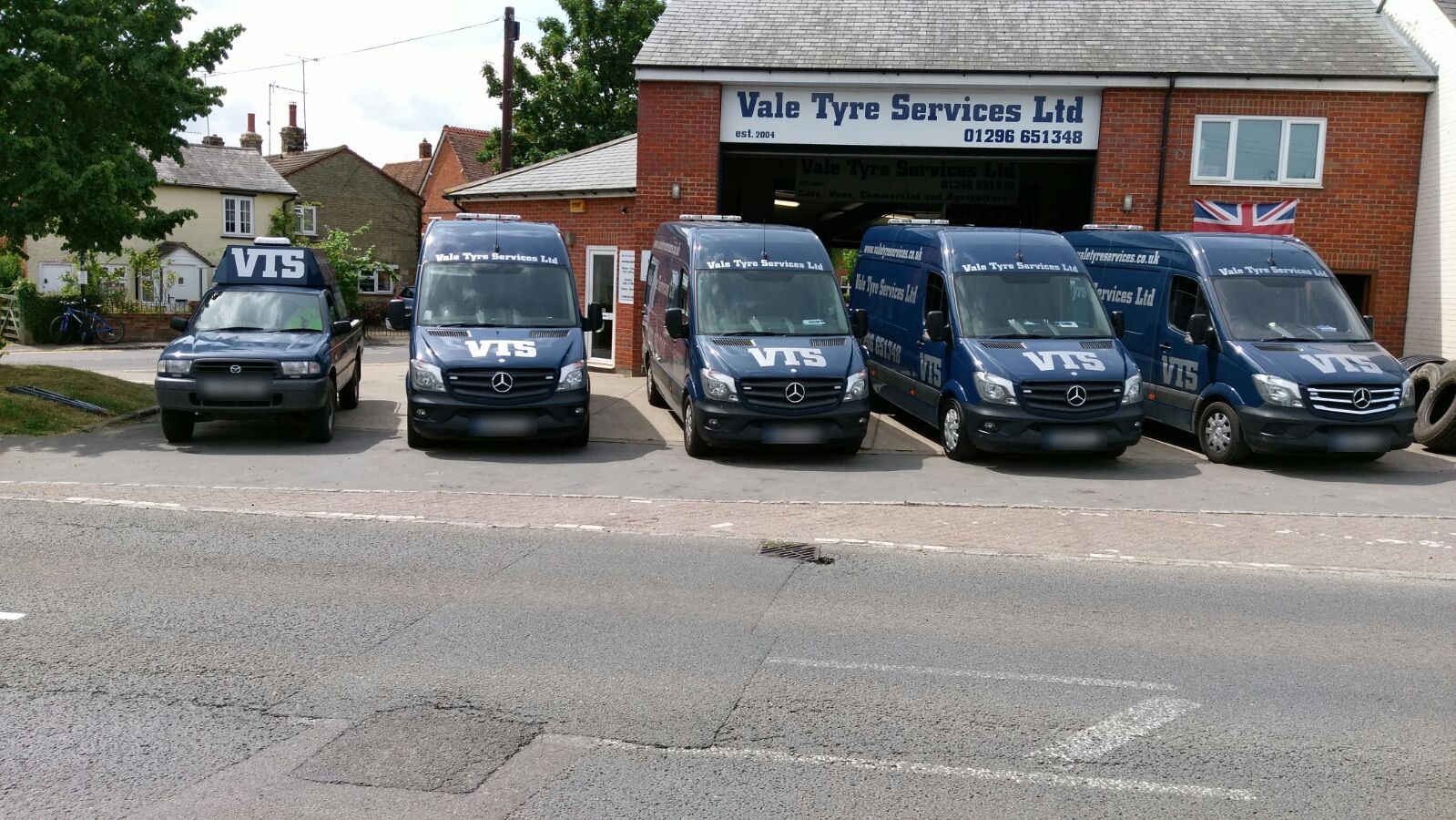 Five liveried Vale Tyre Services vans and a VTS 4x4 lined up outside the brick workshop on Waddesdon High Street