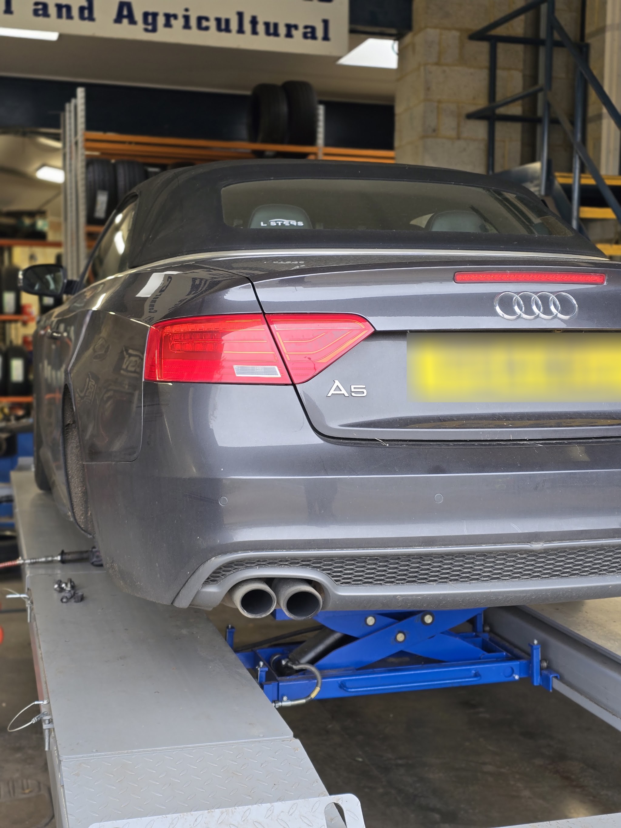 Grey Audi A5 raised on the scissor lift under the Commercial and Agricultural sign