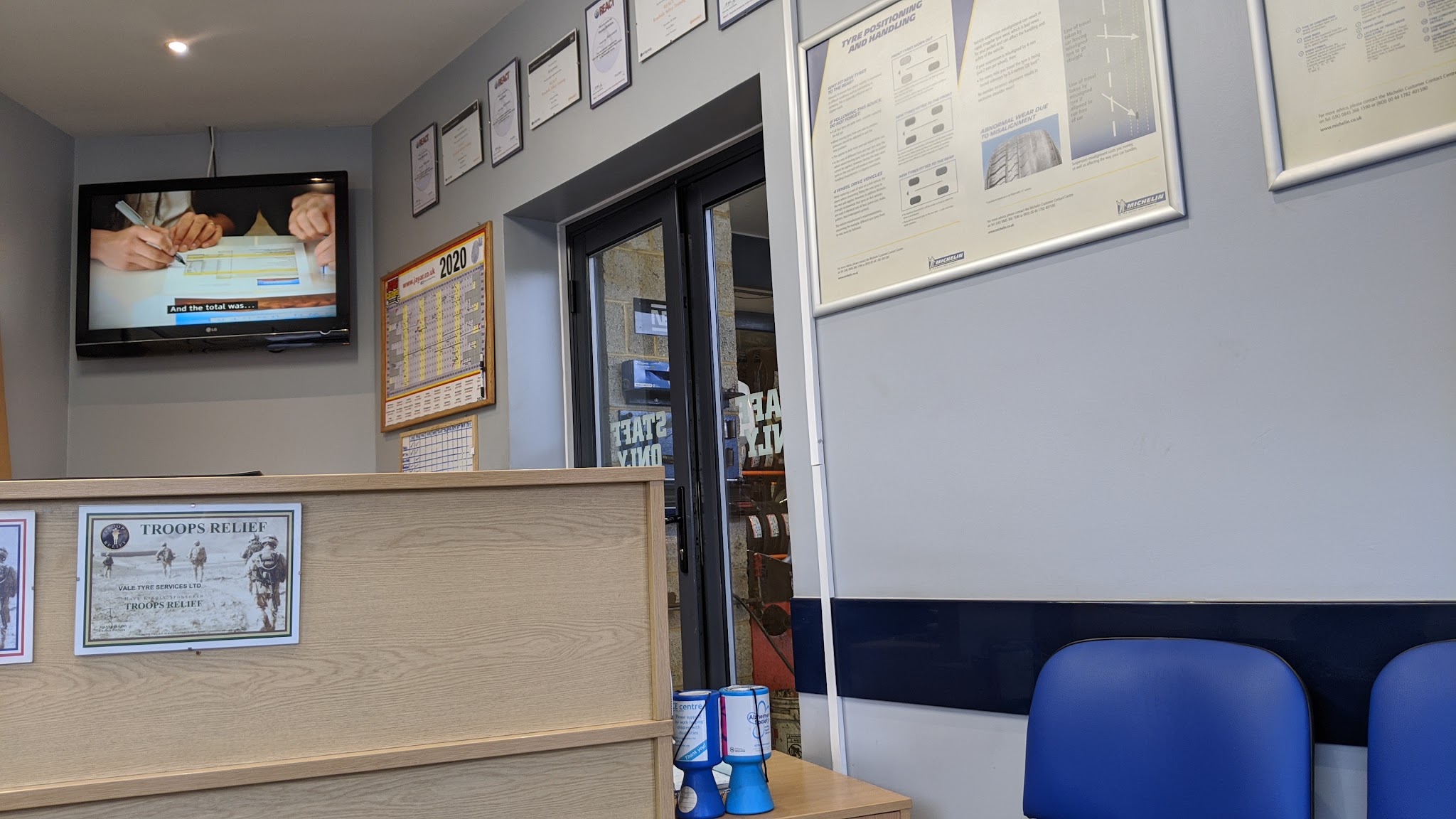 The reception with its counter, framed certificates and blue chairs