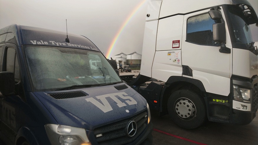 A Vale Tyre Services van parked beside a white lorry cab, a rainbow over the yard